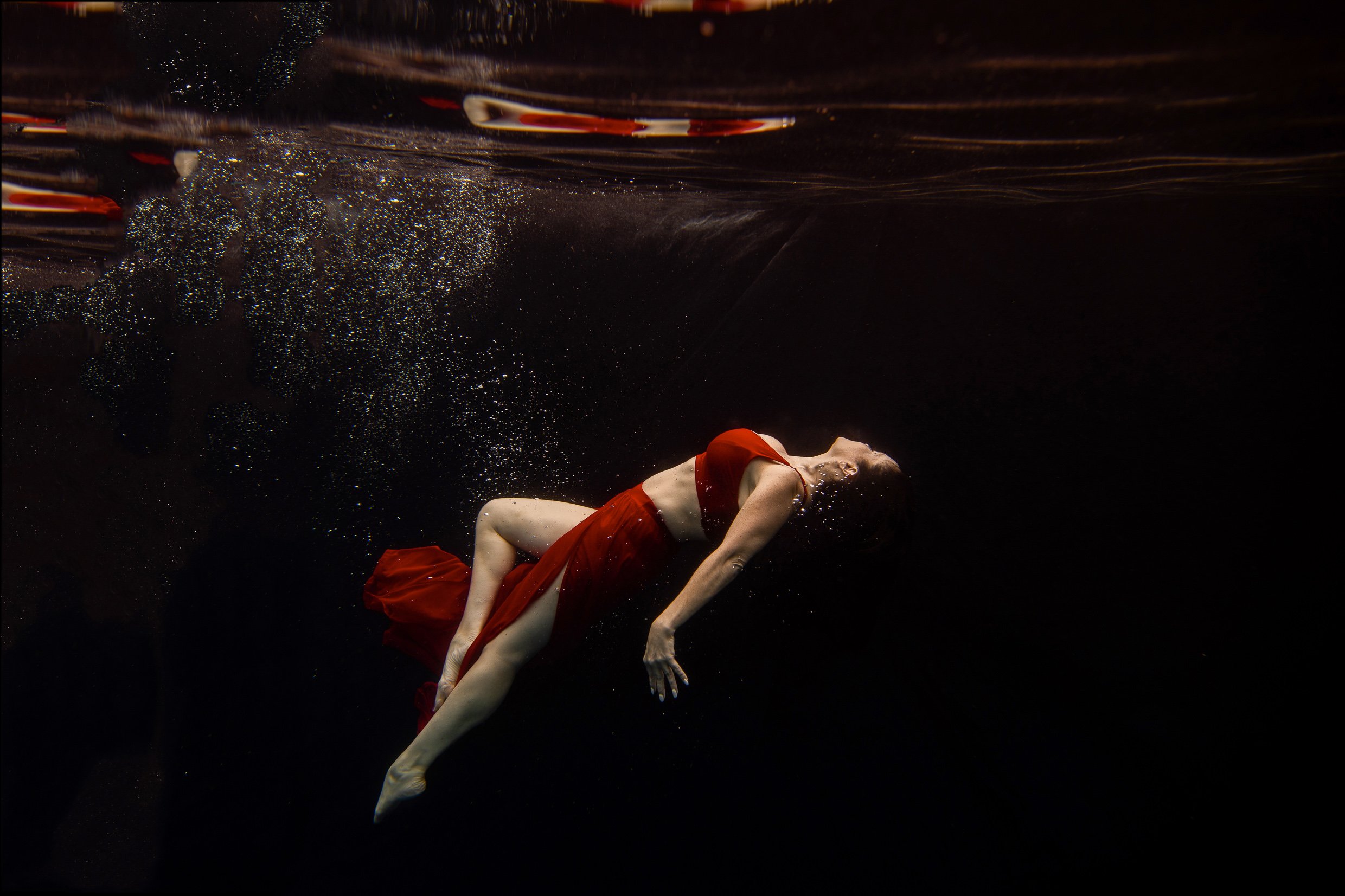 A boudoir client swims underwater in Upstate New York pool